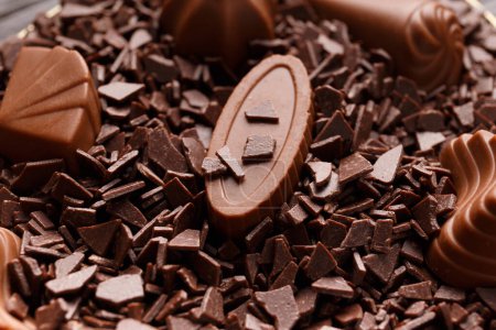 Téléchargez les photos : Magnifiques bonbons au chocolat au lait trempés dans des pépites de chocolat gros plan, concept de fabrication de bonbons au chocolat, fond de chocolat. - en image libre de droit