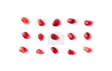 Foto de Red grains of a ripe pomegranate are neatly laid out on a white background top view. Pomegranate grains on isolated. Background of pomegranate seeds. - Imagen libre de derechos