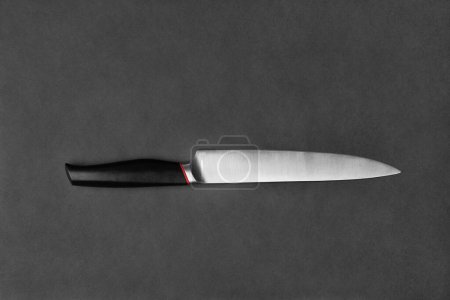 Téléchargez les photos : Kitchen knife with a black handle on a black background. Large knife on a dark background. Kitchenware. Knife with a wide blade. - en image libre de droit
