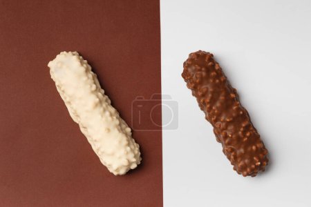Téléchargez les photos : Chocolat blanc et noir sur fond brun et blanc, vue de dessus. Représentation conceptuelle de deux contraires dans le thème du chocolat. Deux barres de chocolat sur fond contrasté - en image libre de droit