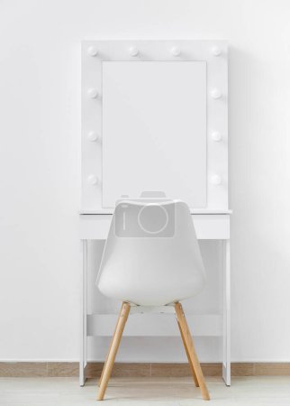 Téléchargez les photos : Table de toilette blanche pour le maquillage avec un grand miroir et des lampes, une chaise blanche sur le fond du mur. Maquilleur lieu de travail, dressing moderne. - en image libre de droit