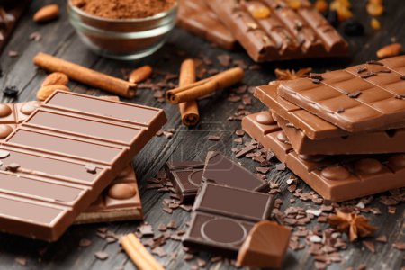 Foto de Chocolate entero y roto, barras de chocolate, caramelos, chispas de chocolate sobre un fondo de madera oscura - Imagen libre de derechos