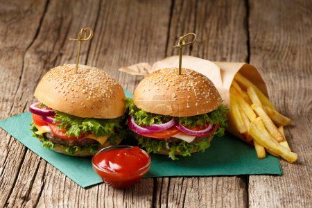Photo for Two hamburgers, french fries and sauces on a rustic wooden background. Fast food, homemade burgers - Royalty Free Image