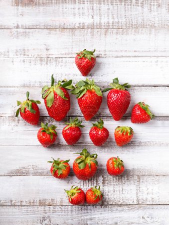 Photo for Berries of large ripe fresh organic strawberries on a wooden background close-up, top view, with space for text. - Royalty Free Image