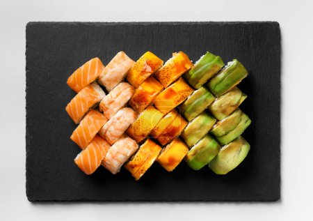 Téléchargez les photos : Ensemble de petits pains colorés avec crevettes, saumon, avocat, fromage sur une assiette en pierre noire, vue sur le dessus. Cuisine asiatique, sushi, fruits de mer. - en image libre de droit