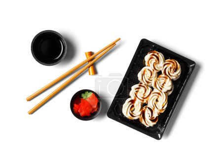 Téléchargez les photos : Rouleaux de sushi au saumon, garnis de fromage à la crème et sauce dans un emballage en plastique, baguettes, gingembre, sauce sur fond blanc. japonais, cuisine asiatique, livraison de sushi. - en image libre de droit