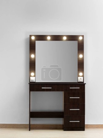 Téléchargez les photos : Table de toilette maquillage sombre avec un grand miroir et des lampes contre un mur blanc. Maquilleur, vestiaire moderne. - en image libre de droit
