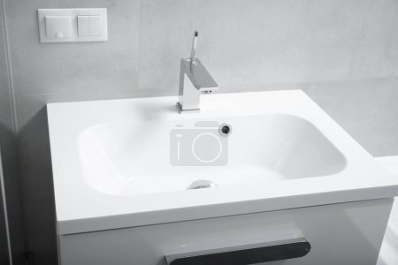 Photo for Modern bathroom interior, white washbasin with drawers, chrome faucet, socket and switch on the wall. Bathroom interior with sink and faucet. - Royalty Free Image
