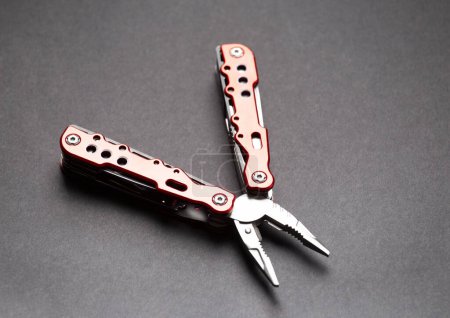 Photo for Universal multifunctional knife pliers with different nozzles and a red handle on a black background. Versatile camping knife. Multifunctional tool. - Royalty Free Image