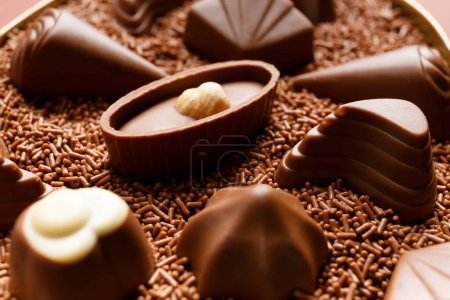 Téléchargez les photos : Magnifiques bonbons au chocolat au lait trempés dans des pépites de chocolat gros plan, concept de fabrication de bonbons au chocolat, fond de chocolat. - en image libre de droit