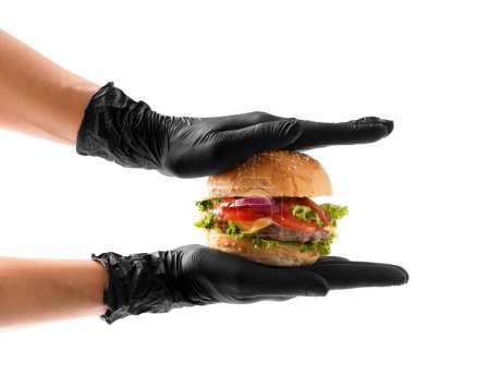 Photo for Hands in black gloves hold a juicy, appetizing beef burger on a white background. Hamburger in hands isolated. Banner, fast food advertising. - Royalty Free Image
