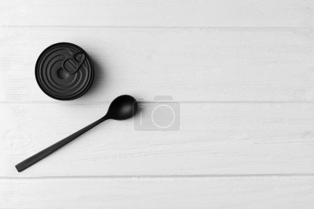 Foto de Lata cerrada redonda mate negra y cuchara negra sobre fondo de madera gris vista superior con espacio para texto, conservas, conservas. - Imagen libre de derechos