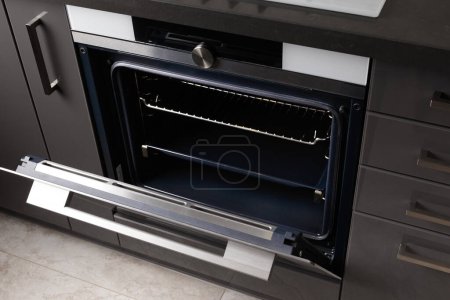 Photo for Built-in electric oven with an open door in the interior of the kitchen. Oven with display, convection. Built-in appliances for the kitchen. - Royalty Free Image