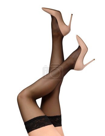 Photo for Slender female legs in black stockings with a beautiful openwork elastic band and elegant beige high-heeled shoes on a white background, isolated. Close-up of the graceful legs of a girl in stockings - Royalty Free Image