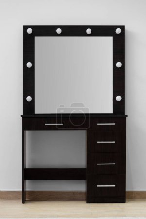 Téléchargez les photos : Table de toilette maquillage sombre avec un grand miroir et des lampes contre un mur blanc. Maquilleur, vestiaire moderne. - en image libre de droit