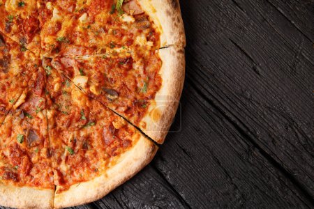 Téléchargez les photos : Pizza italienne avec plusieurs types de viande sur un fond en bois noir, vue du dessus, espace de copie. - en image libre de droit