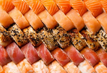 Foto de Un gran conjunto de rollos de sushi con camarones, salmón, atún, anguila, vista superior, primer plano. Entrega de sushi. Rollos como fondo. - Imagen libre de derechos