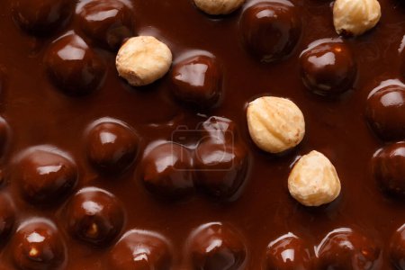 Foto de Background of dark chocolate and hazelnuts. Black handmade chocolate with nuts top view macro shot. - Imagen libre de derechos