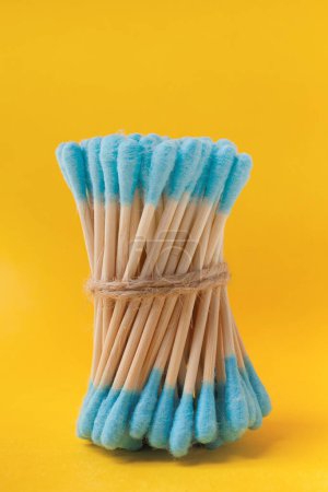 Foto de Un manojo de bastoncillos de algodón de bambú azul se pega sobre un fondo amarillo. El concepto de artículos de higiene a partir de materiales naturales, ecológicos y biodegradables. - Imagen libre de derechos