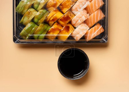 Téléchargez les photos : Un ensemble de rouleaux de sushi multicolores lumineux avec crevettes, saumon, avocat dans un emballage en plastique sur un fond clair, vue de dessus. Livraison de sushi - en image libre de droit