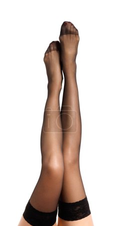 Jambes femelles minces en bas noirs sont soulevées sur un fond blanc. Gros plan des jambes gracieuses d'une fille pointant magnifiquement sur blanc isolé.