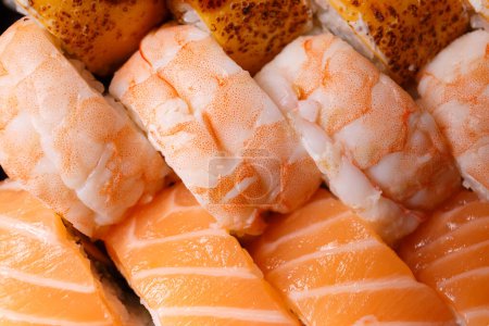 Téléchargez les photos : Un grand ensemble de rouleaux de sushi avec crevettes, saumon, thon, vue de dessus, gros plan. Livraison de sushi. Rouleaux comme arrière-plan. - en image libre de droit