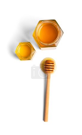 Foto de Composición creativa de la miel en frascos abiertos en forma de panales y una cacerola de madera sobre una vista superior de fondo blanco. El concepto de productos de abejas orgánicas. Miel en aislamiento. - Imagen libre de derechos