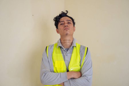 Photo for Man worker Indonesian arrogant gesture wear vest. The photo is suitable to use for engineer poster and safety content media. - Royalty Free Image