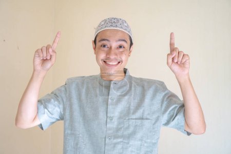 Téléchargez les photos : Homme musulman asiatique pointant le geste de lien lorsque la célébration du Ramadan. La photo est appropriée pour l'affiche Ramadhan et les médias de contenu musulman. - en image libre de droit