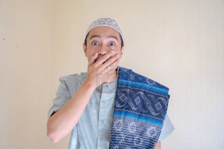 Téléchargez les photos : L'homme musulman asiatique a surpris l'expression en regardant la caméra lors de la célébration du Ramadan. La photo est appropriée pour l'affiche Ramadhan et les médias de contenu musulman. - en image libre de droit