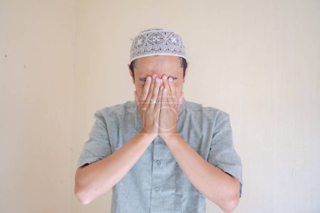 Téléchargez les photos : Homme musulman asiatique geste triste quand célébration du Ramadan. La photo est appropriée pour l'affiche Ramadhan et les médias de contenu musulman. - en image libre de droit