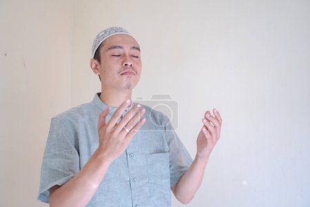 Téléchargez les photos : Homme musulman asiatique prière geste quand célébration du Ramadan. La photo est appropriée pour l'affiche Ramadhan et les médias de contenu musulman. - en image libre de droit