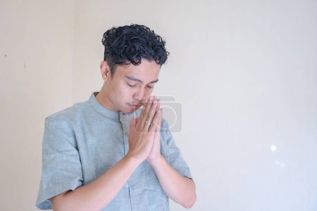 Hombre musulmán asiático gesto de oración cuando la celebración del Ramadán. La foto es adecuada para usar para póster de Ramadán y medios de contenido musulmán.