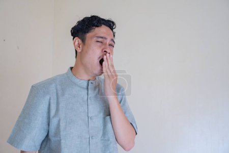 Téléchargez les photos : Homme musulman asiatique geste somnolent quand célébration du Ramadan. La photo est appropriée pour l'affiche Ramadhan et les médias de contenu musulman. - en image libre de droit
