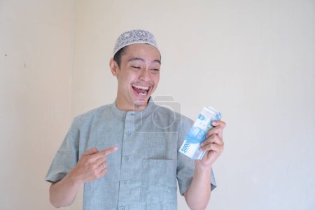 Téléchargez les photos : Musulman Asiatique heureux, souriant quand a eu THR argent Ramadan célébration. La photo est appropriée pour l'affiche Ramadhan et les médias de contenu musulman. - en image libre de droit
