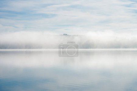 Mistyczny mglisty krajobraz nad jeziorem. Natura we mgle. Odpoczynek i relaks.