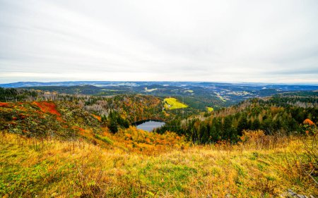Autumnal landscape on the Feldberg in the Black Forest with a view of the Feldsee and the surrounding nature with forests and hills.
