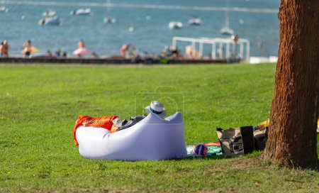 Photo for Woman wearing a hat lying on an inflatable sofa on the lawn by the sea - Royalty Free Image