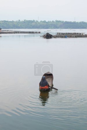 Foto de A woman paddling a boat early in the morning on the lake - Imagen libre de derechos
