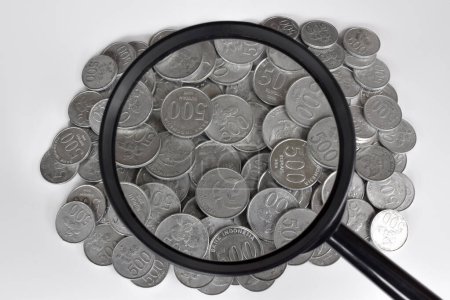 Foto de Pile of Indonesian 500 rupiah coins with foreground magnifying glasses. Money concept - Imagen libre de derechos