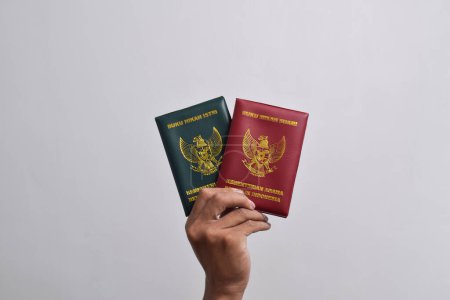 Téléchargez les photos : Mains tenant le livre de mariage, mari et femme, ministère de la religion de la République d'Indonésie isolé sur fond blanc - en image libre de droit