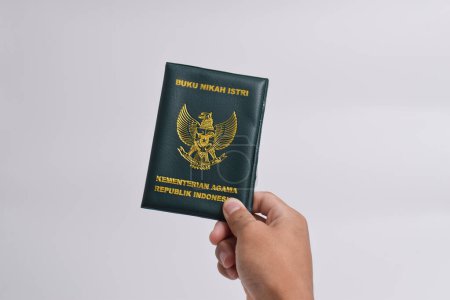 Hand in Hand mit dem Ehebuch der Ehefrau, Ministerium für Religion der Republik Indonesien isoliert auf weißem Hintergrund