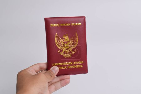 Hand in Hand mit dem Ehebuch des Ehemanns, Ministerium für Religion der Republik Indonesien isoliert auf weißem Hintergrund