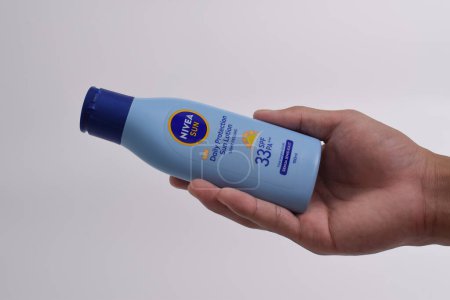 Photo for Pasuruan - February 19, 2024 : Hand holding a Nivea daily protection sun lotion isolated on white background. Nivea is a German personal care brand that specializes in skin- and body-care products - Royalty Free Image