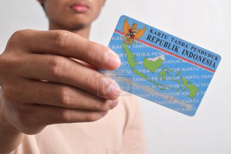Una persona muestra y sostiene tarjetas de identidad indonesias (KTP) sobre fondo blanco. Enfoque selectivo