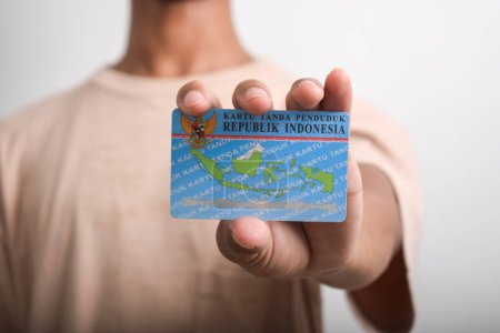 A person shows and holds Indonesian identity cards (KTP) on white background. Selective focus