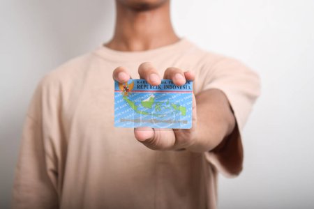 A person shows and holds Indonesian identity cards (KTP) on white background. Selective focus