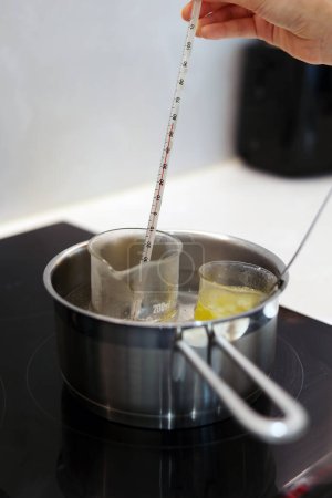 Téléchargez les photos : Heat beakers of water and jojoba oil in boiling water, record the temperature with a thermometer - en image libre de droit