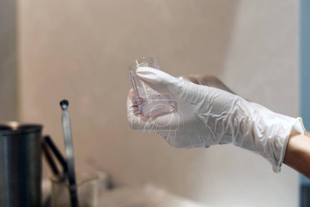 Téléchargez les photos : Gloved hands holding the cosmetic empty bottle in the laboratory - en image libre de droit
