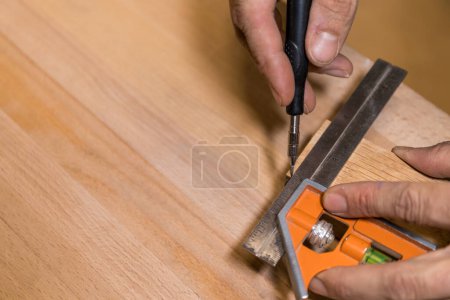 Horizontal photo Craftsman's hands are shown marking a wooden plank with a metal square and scriber, ensuring accurate and straight cuts in woodworking. Copy space. Business concept.